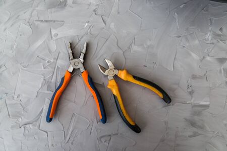 Wire cutters and pliers with orange black handles on gray background
