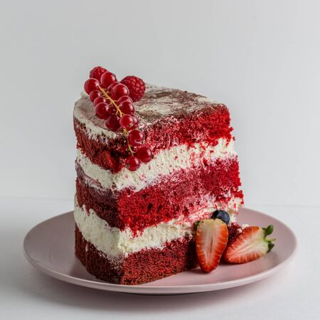 Slice of delicious homemade red velvet cake with cream , strawberries .