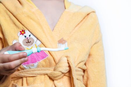 Childs hands holding big tooth and toothbrush on white background.の写真素材