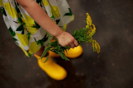Little blond girl in a yellow boots in the puddleの写真素材