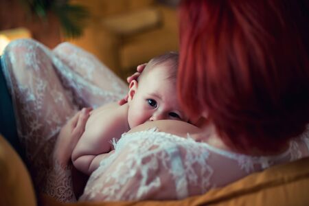 Mother in white dress breastfeeding her baby boyの写真素材