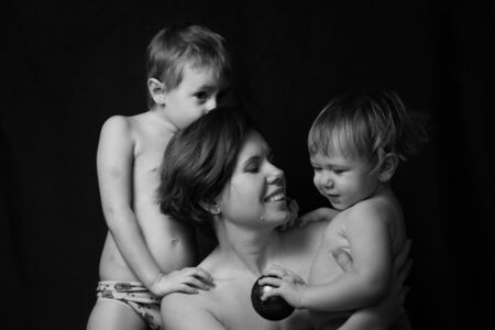 Adorable sweet young mother with cute little children on black backgroundの写真素材