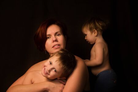 Adorable sweet young mother with cute little children on black backgroundの写真素材
