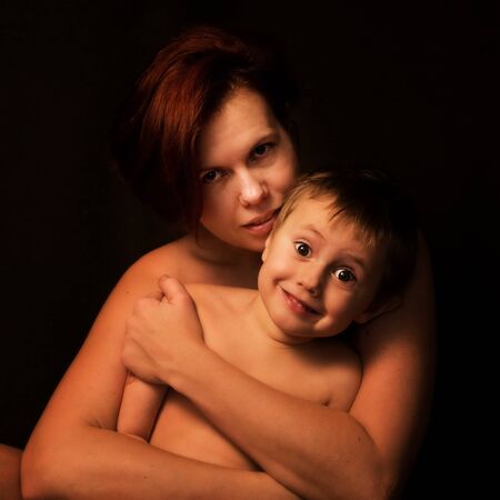 Adorable sweet young mother with cute little children on black backgroundの写真素材