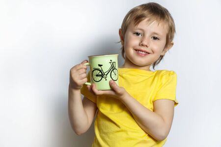 little cute caucasian girl holding a mug of tea or juice with both handsの写真素材