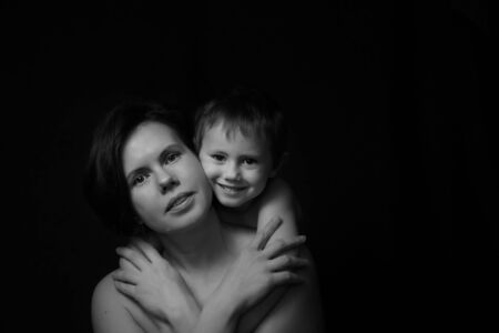 Adorable sweet young mother with cute little children on black backgroundの写真素材