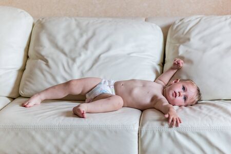 Cute baby girl in diapers lying on bedの写真素材