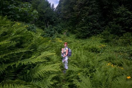 Woman Hiker trekking in mountains with child in backpack .の写真素材