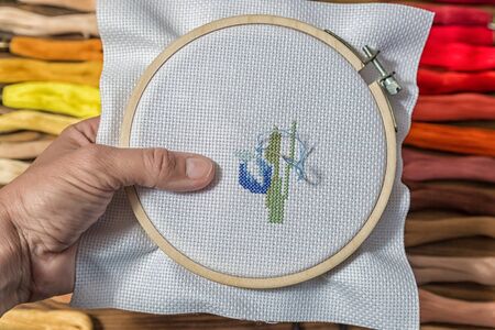 Embroidery cross stitching in the lady's hands.