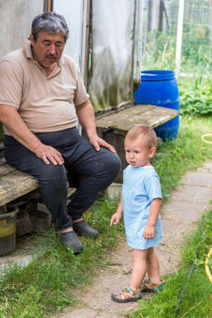 An elderly man walks with a child in the fresh air.
