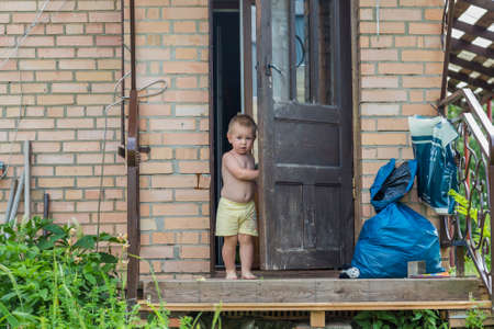Little boy is opening door from inside the village houseの写真素材