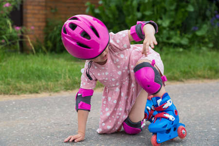 A little girl roller skating in full protection fell on the asphaltの写真素材
