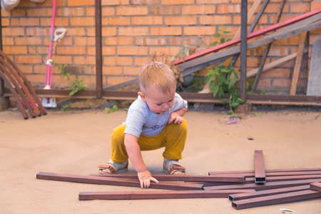 Boy is playing with iron building materials near the garage while parents don't see him. Renovation...
