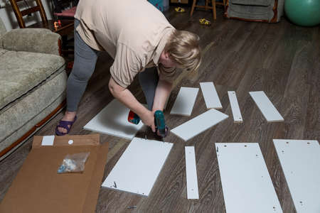 The Woman assembles wardrobe with a screwdriver