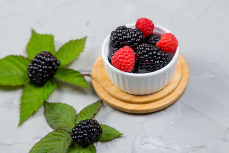Ripe sweet blackberry in wooden wicker bowl on gray concrete background.の写真素材