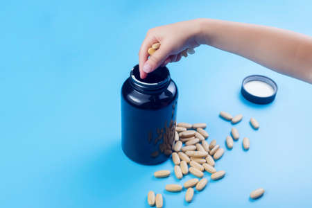 Close up view of child hands with pills, young child play alone with pills tablets at home.