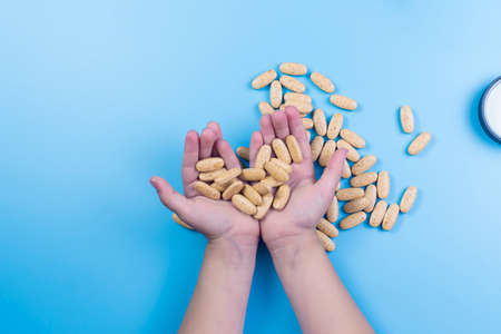 Close up view of child hands with pills, young child play alone with pills tablets at home.