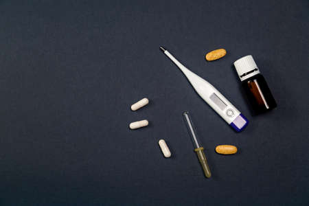 cold season is open. Cold medicines, pills, drops, pipette, thermometer on a solid black backgroundの写真素材