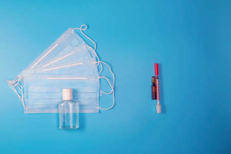 Mask and hand sanitizer on one side and vaccine with syringe on the other. The dilemma is to get vaccinated against covid or not.の写真素材