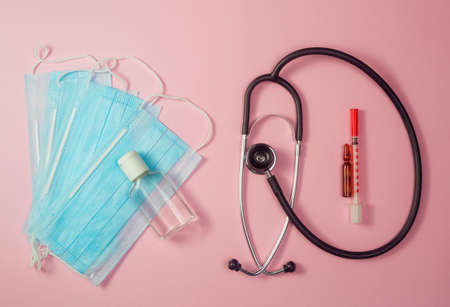 Covid-19, coronavirus treatment. Pills, stethoscope and medical masks, vaccine on pink background.の写真素材
