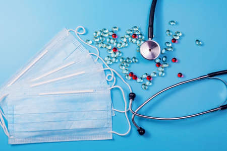 Covid-19, coronavirus treatment. Pills, stethoscope and medical masks on blue background.の写真素材