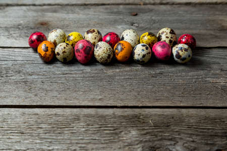Multi-color dyed easter eggs arranged in a row on wooden background. Easter background with space...