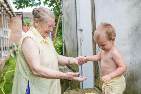 Grandmother plays with a small grandson in the summer cottage, the child is happyの写真素材