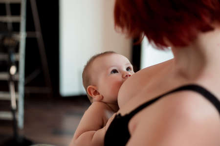 A young mother is breastfeeding her little child and looking at him tenderlyの写真素材