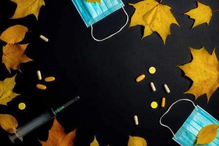 Autumn fallen leaves and medical masks and medicines on black backgroundの写真素材