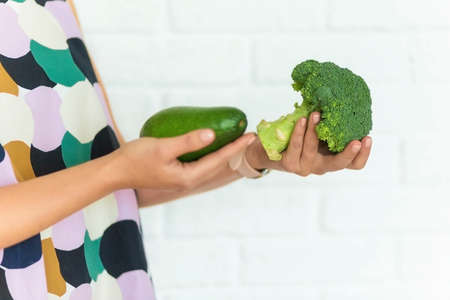 .female hands holding broccoli and avocadoの写真素材