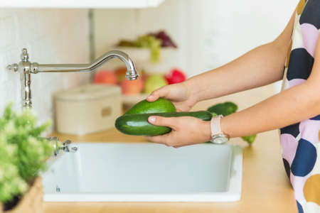 .female hands washing green vegetables over the sinkの写真素材