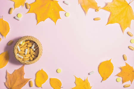 Autumn fallen leaves and medicines on pink background.の写真素材