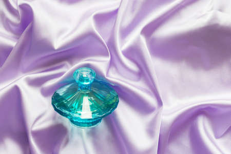 Perfume bottle on lilac silk folded fabric background. Luxery Scent fragrance cosmetic beauty product.の写真素材