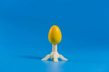 Colored easter plastic egg on a stand in the form of a rocket on a blue backgroundの写真素材