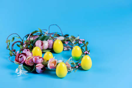 Colored Easter wreath and plastic eggs on a blue background.