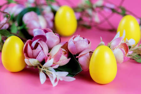 Colored Easter wreath and plastic eggs on a pink background.