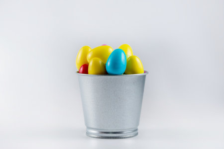 Colorful Plastic Easter Eggs in a metal bucket on white background.の写真素材