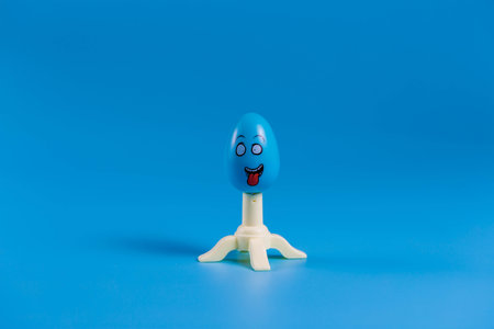 .Colored easter plastic egg on a stand in the form of a rocket on a blue background