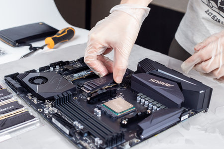 Moscow, Russia - 25 Dec 2020: Technician installing a heatsink on top of a m2 hard drive. Electronic repair shop, technology renovation, business, concept repairs.のeditorial素材