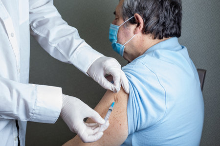 Antivirus vaccination for older people in clinic. General practitioner vaccinating an elderly patient against flu, influenza, pneumoniaの写真素材