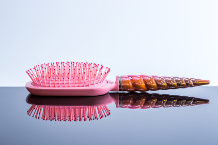 Beautiful pink hairbrush on a black glossy surface. Women's Hair Care Accessories. Side viewの写真素材