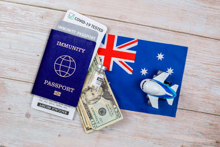 Concept of immunity to coronavirus. Certificate stating that person is not contagious. Passport with note covid-19 test passed, money, vaccine bottle and a toy plane on flag of New Zelandの写真素材