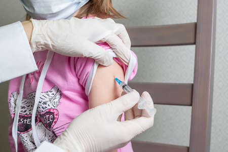 A doctor holding syringe subcutaneous vaccine for child in the medical office, A 5-year-old...