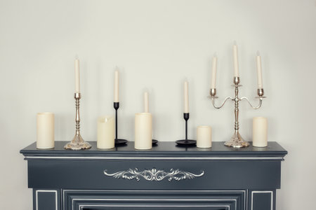 Candles of various types and sizes with and without candlesticks on the imitation fireplace countertop near the wallの写真素材
