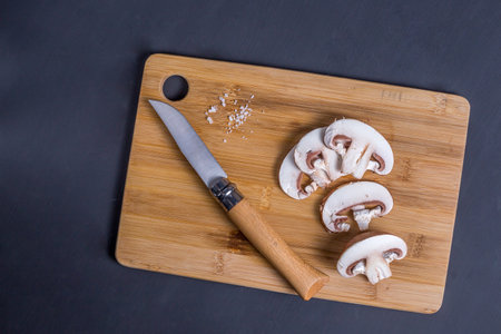 Royal champignons, Parisian champignons, mushrooms on bamboo wooden chopping board. Dark wooden...