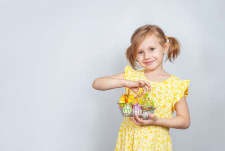 Portrait of a little cute Caucasian smiling girl with a shopping basket filled with Easter decorations. Easter background with place to insert text.の写真素材