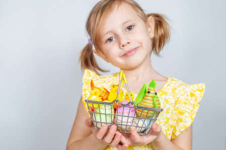 Portrait of a little cute Caucasian smiling girl with a shopping basket filled with Easter decorations. Easter background with place to insert text.の写真素材