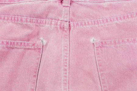 A close-up of a frayed pink jeans pocket, a torn off pocket.の写真素材