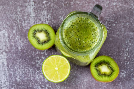 Close-up on the texture of smoothies in a mug and lying nearby halves of fruits on a gray background, top view, layout.の写真素材