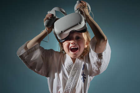 Caucasian little girl in karate uniform playing video games with VR headsetの写真素材